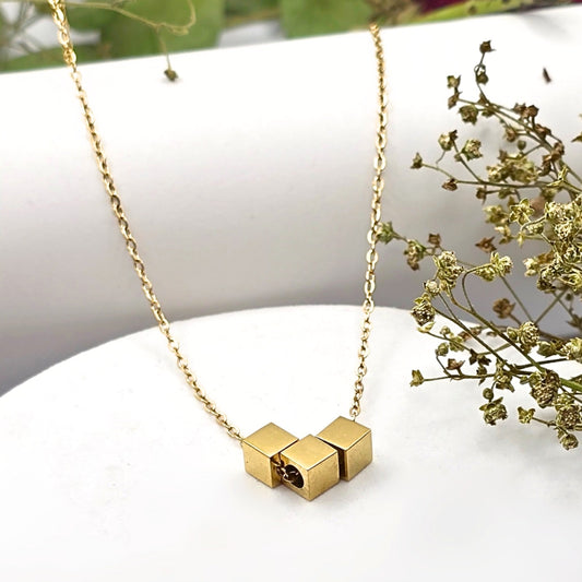 Kubic Necklace 
Crafted from durable stainless steel with sleek gold plating, the Kubic Necklace boasts versatile square beads that glide effortlessly along its 45 cm chain.