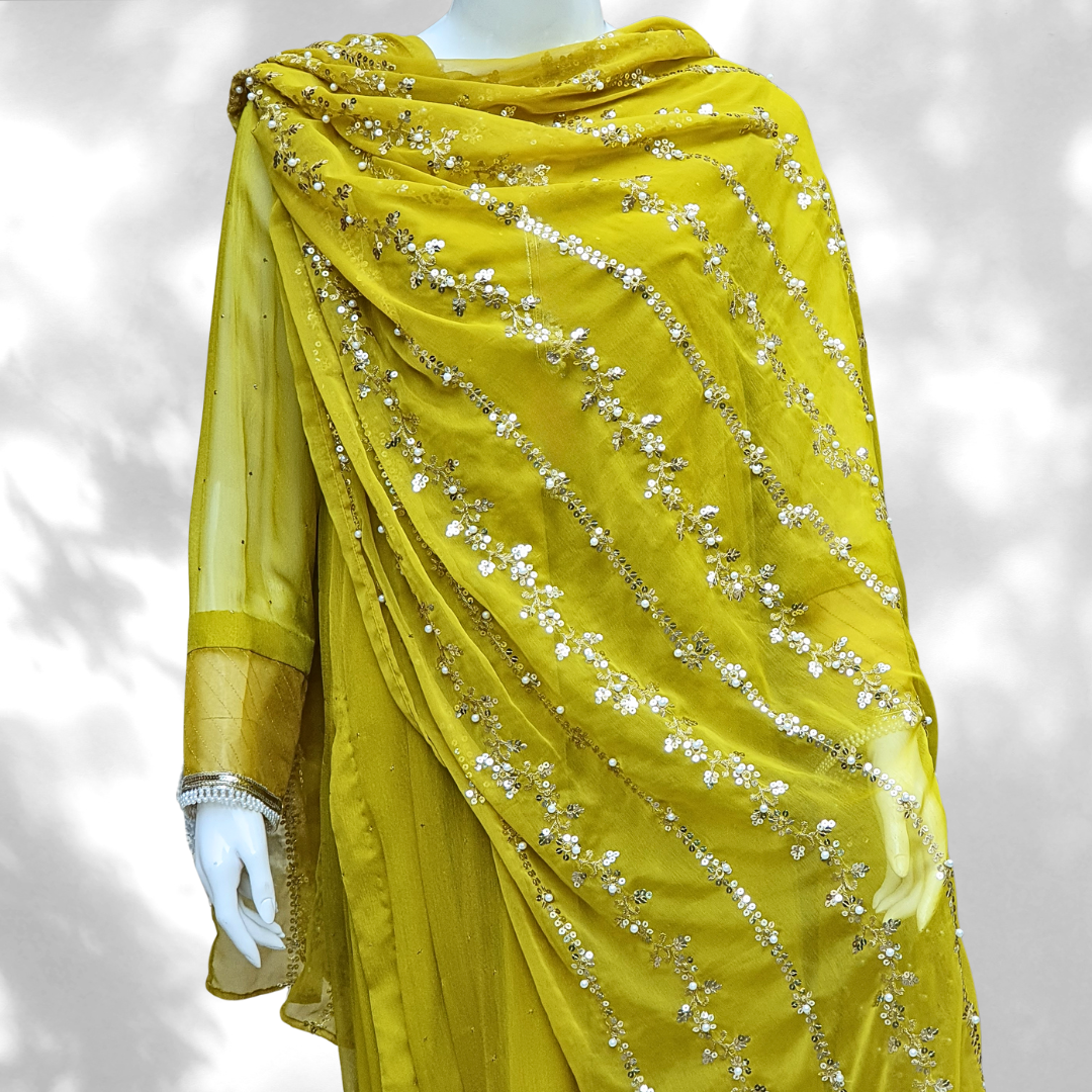 This 3-piece Golden Radiance Mehndi Ensemble features a Mukesh chiffon shirt with organza details on the sleeves and daman. The neckline is embellished with pearls and sequins, while the organza dupatta and silky plazzos add an elegant touch.