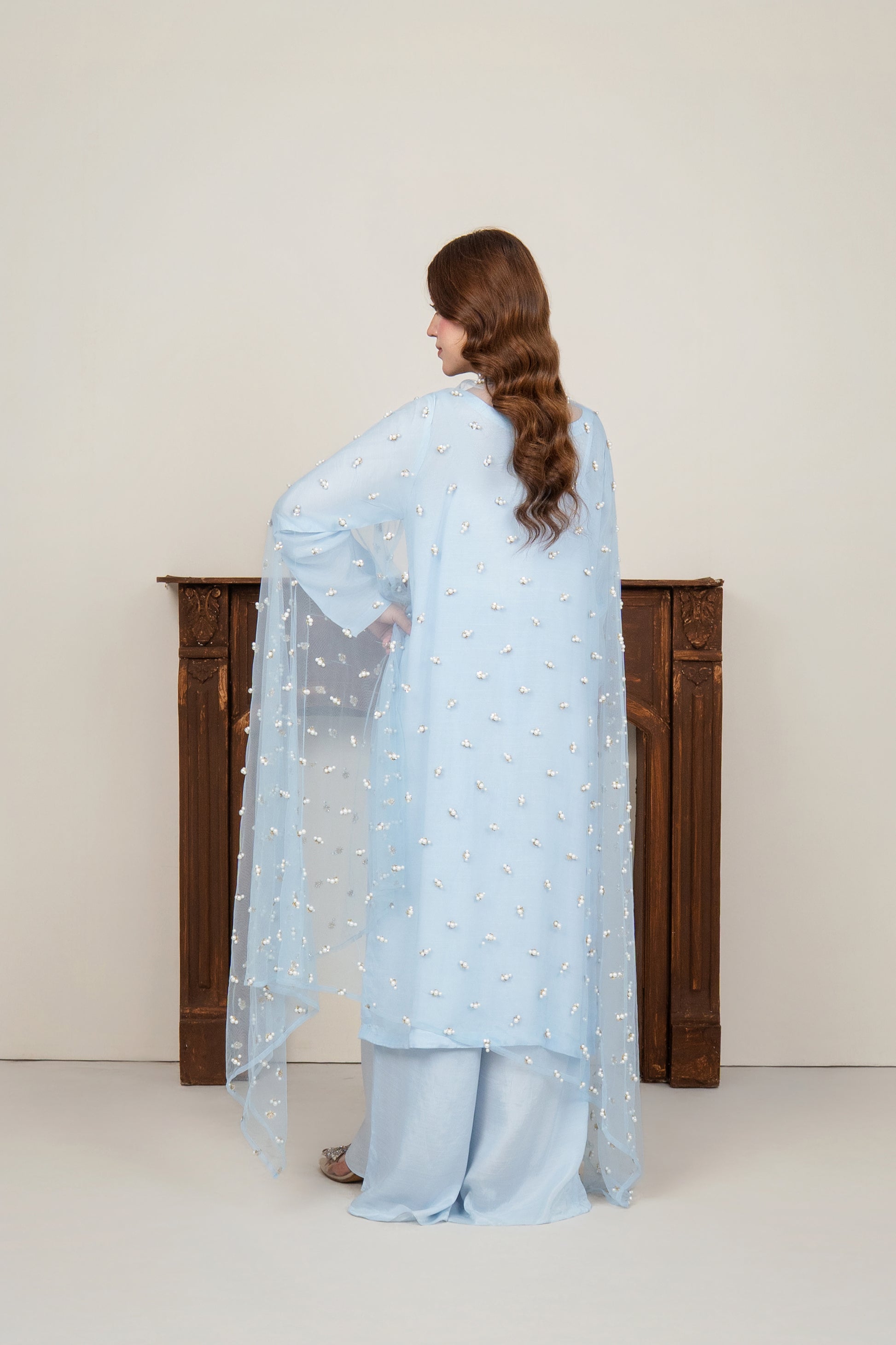 Back view of the 3-piece ice blue raw silk ensemble, showing the sheer net dupatta embellished with evenly spaced punched pearls.